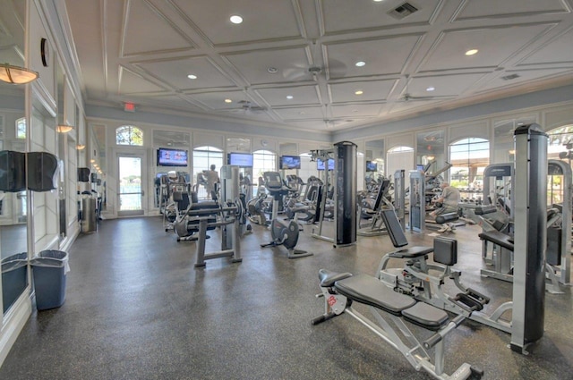 gym featuring coffered ceiling, ceiling fan, and plenty of natural light