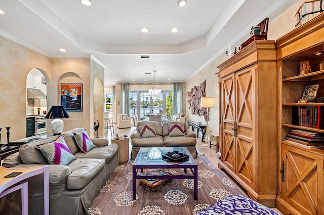 living room with ornamental molding, a textured ceiling, and an inviting chandelier