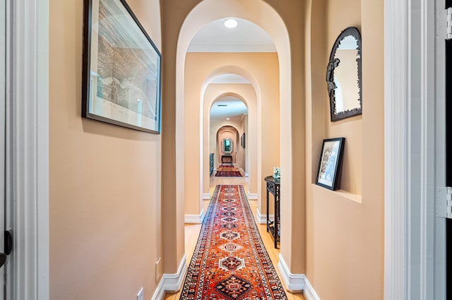 corridor with hardwood / wood-style floors and ornamental molding