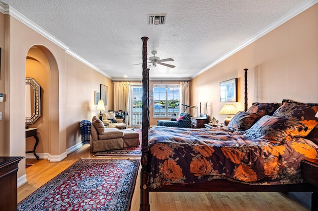 bedroom with ornamental molding, light hardwood / wood-style floors, ceiling fan, and a textured ceiling