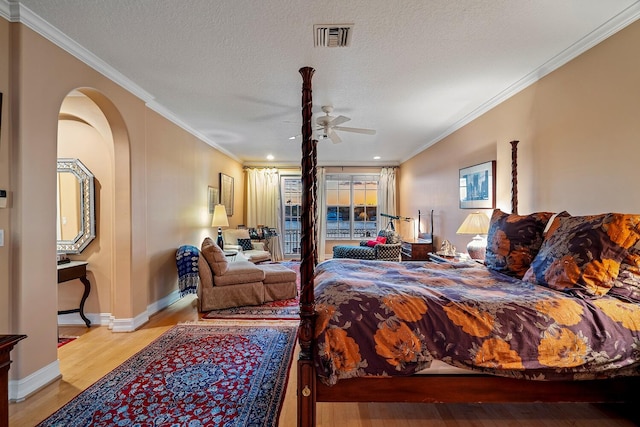 bedroom featuring light hardwood / wood-style floors, crown molding, ceiling fan, and a textured ceiling