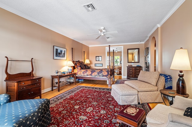 living room with ornamental molding, ceiling fan, light wood-type flooring, and a textured ceiling