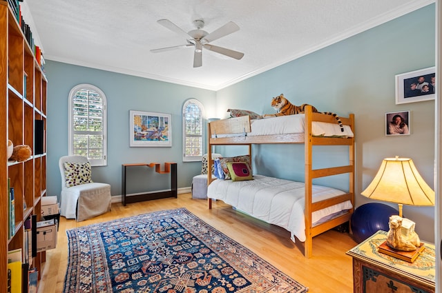 bedroom with ornamental molding, ceiling fan, light wood-type flooring, and a textured ceiling