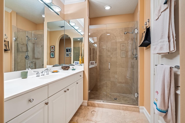 bathroom featuring a shower with shower door, vanity with extensive cabinet space, a textured ceiling, tile floors, and ornamental molding