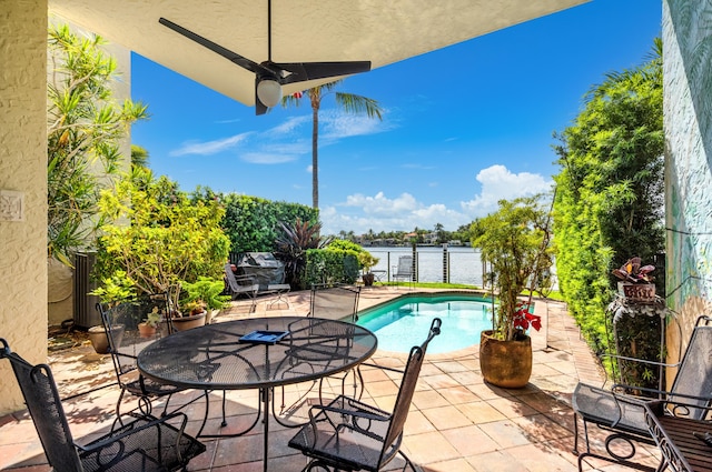 view of patio / terrace with a water view, ceiling fan, and a fenced in pool