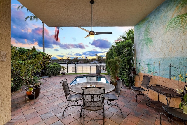 patio terrace at dusk featuring a fenced in pool