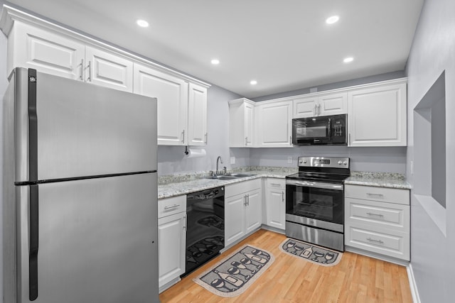 kitchen with light stone counters, white cabinets, sink, light wood-type flooring, and black appliances