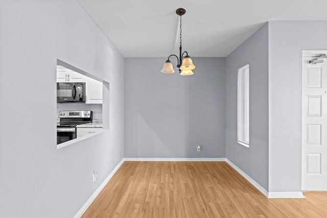 empty room with light hardwood / wood-style flooring and a notable chandelier