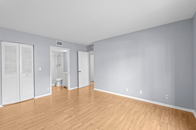 unfurnished bedroom with a closet, light wood-type flooring, and connected bathroom