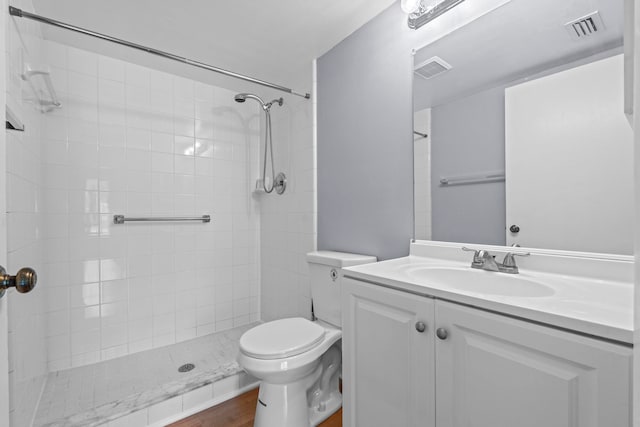 bathroom with a tile shower, oversized vanity, hardwood / wood-style flooring, and toilet