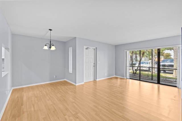 spare room featuring light hardwood / wood-style flooring and a notable chandelier