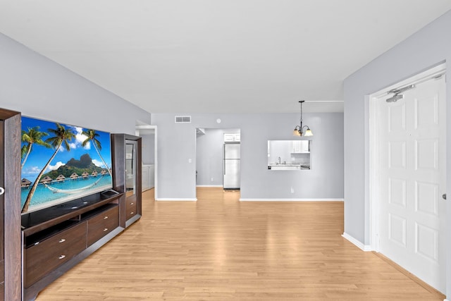 living room with sink, light wood-type flooring, and a chandelier