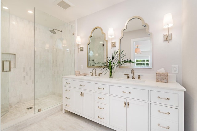 bathroom featuring a shower with door and dual bowl vanity