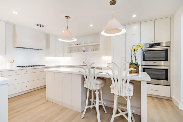 kitchen with light hardwood / wood-style flooring, pendant lighting, a center island, and white cabinetry