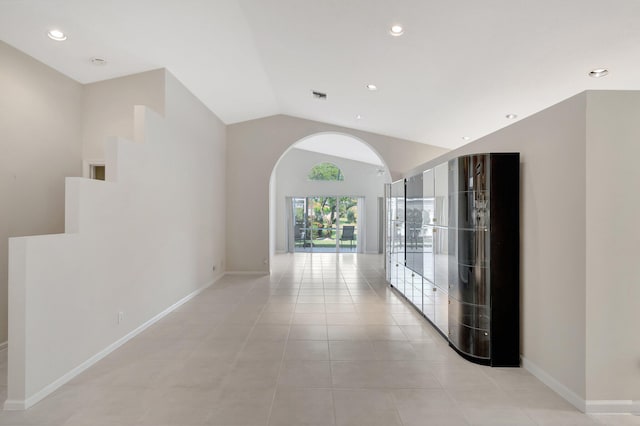 hall with light tile patterned floors and vaulted ceiling