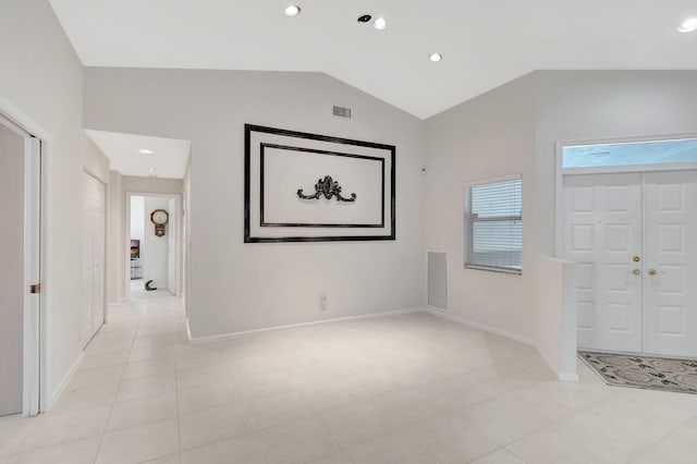 foyer entrance with light tile patterned floors and vaulted ceiling