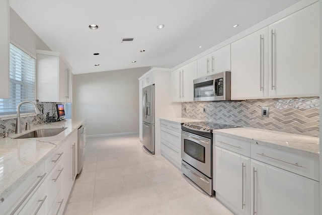 kitchen featuring white cabinets, sink, light stone countertops, and stainless steel appliances