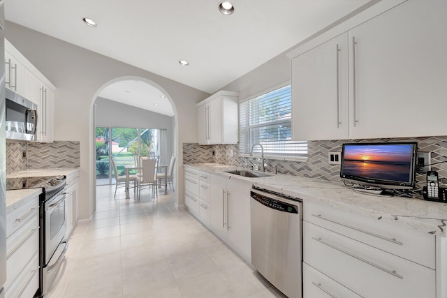 kitchen featuring sink, white cabinetry, stainless steel appliances, and vaulted ceiling