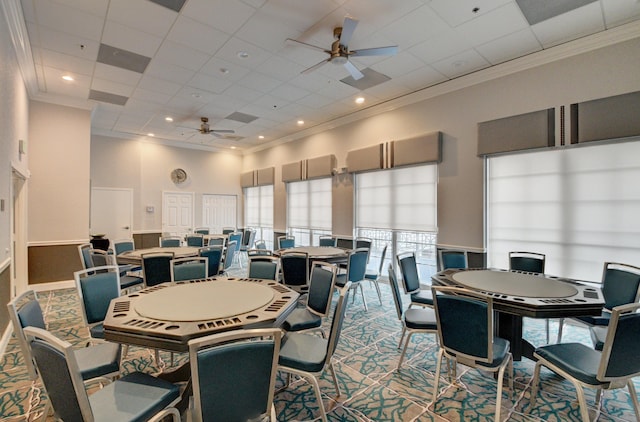 carpeted dining space featuring a paneled ceiling, ceiling fan, a high ceiling, and ornamental molding