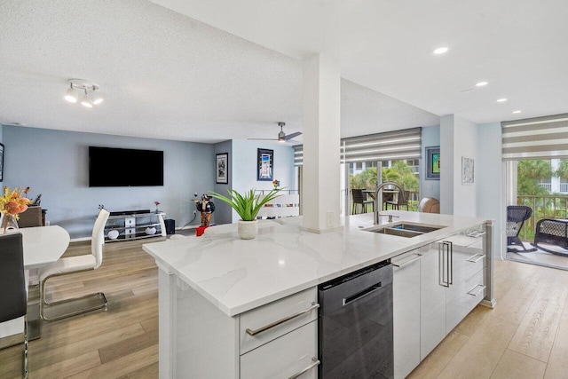 kitchen with light hardwood / wood-style flooring, sink, a center island with sink, and black dishwasher