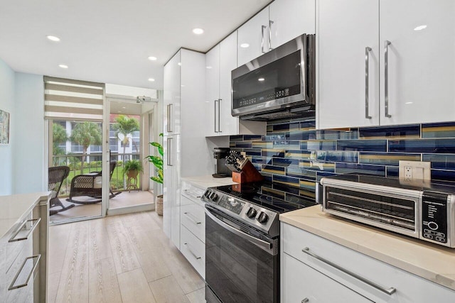 kitchen featuring white cabinets, light wood-type flooring, backsplash, and range with electric cooktop