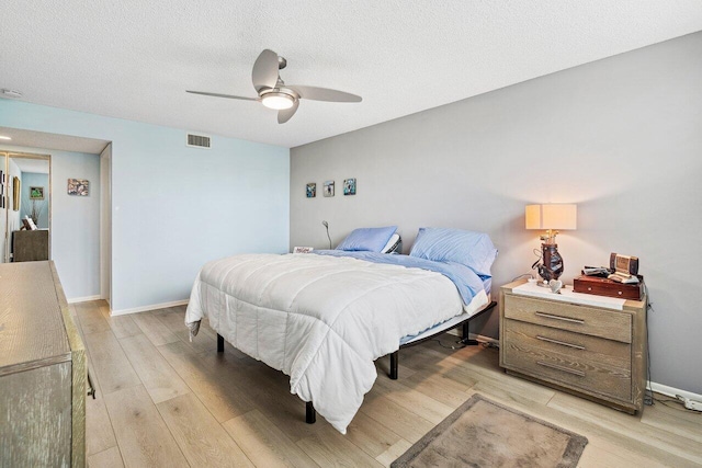 bedroom with light hardwood / wood-style flooring, ceiling fan, and a textured ceiling