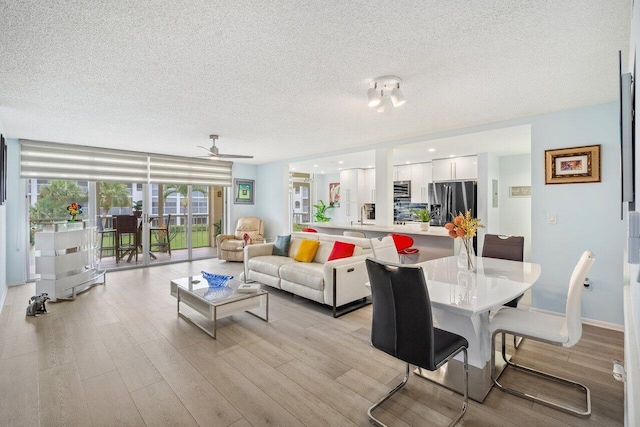 living room featuring a textured ceiling, light hardwood / wood-style flooring, and ceiling fan