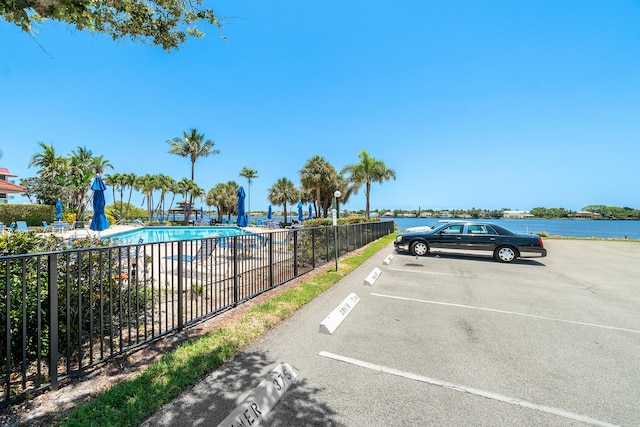 view of car parking with a water view and a community pool