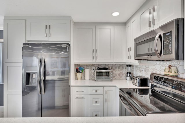 kitchen featuring white cabinets, a toaster, stainless steel appliances, and decorative backsplash