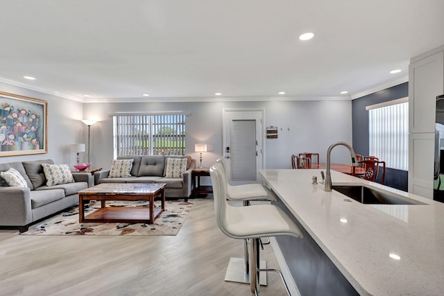 living area with a healthy amount of sunlight, light wood-style floors, ornamental molding, and recessed lighting