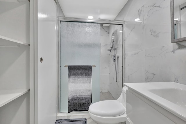 bathroom featuring toilet, tile walls, a marble finish shower, and vanity