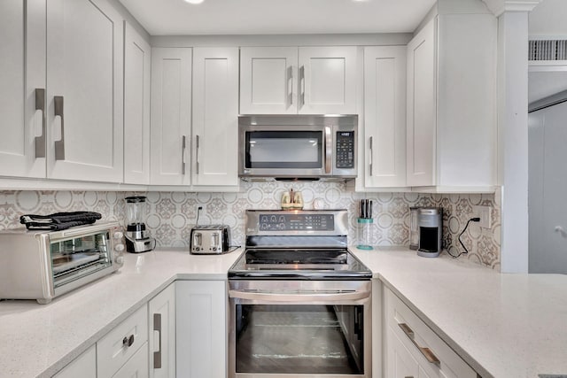 kitchen with a toaster, stainless steel appliances, visible vents, decorative backsplash, and white cabinetry