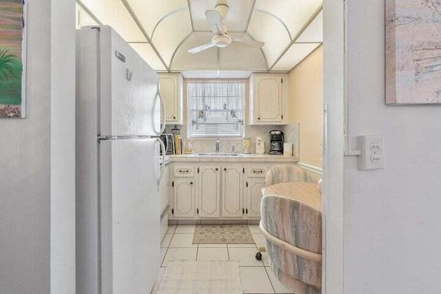 kitchen featuring white refrigerator, ceiling fan, sink, and light tile flooring