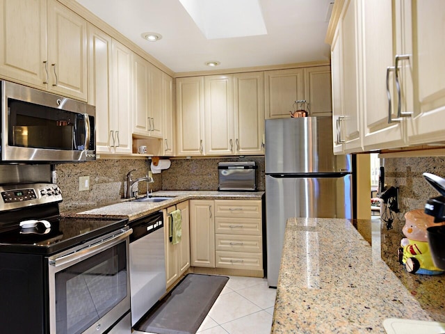 kitchen featuring sink, appliances with stainless steel finishes, tasteful backsplash, and light stone countertops