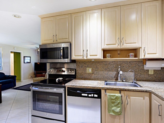 kitchen featuring appliances with stainless steel finishes, tasteful backsplash, sink, and light stone counters