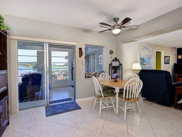 tiled dining area with ceiling fan and a water view