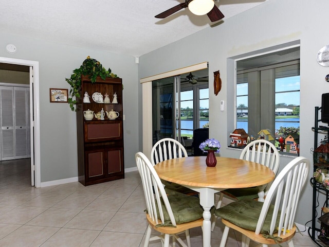 tiled dining room with french doors, ceiling fan, and a water view