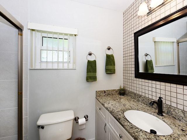 bathroom with vanity with extensive cabinet space, backsplash, toilet, and tile walls