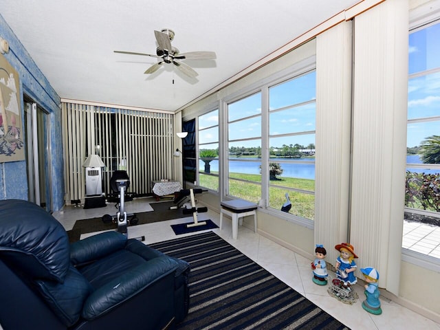 living room featuring ceiling fan, a water view, light tile floors, and plenty of natural light