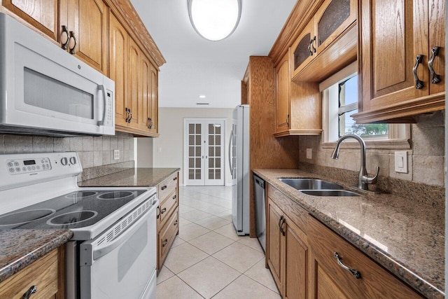 kitchen with dark stone countertops, appliances with stainless steel finishes, sink, and light tile patterned floors