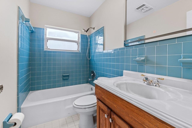 full bathroom with tiled shower / bath, tile walls, vanity, toilet, and tile patterned floors