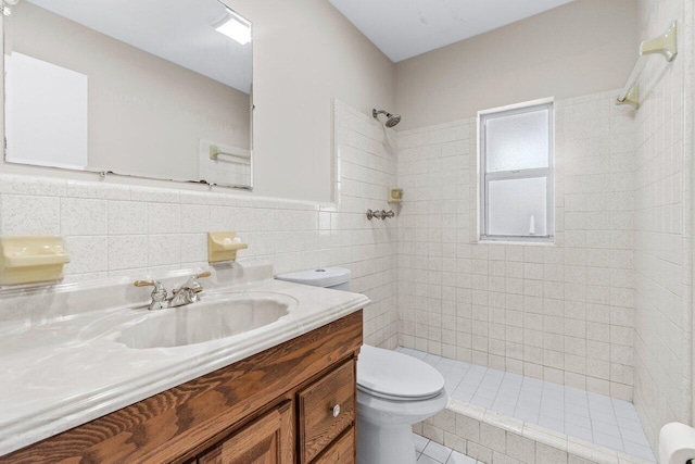 bathroom with vanity, tile walls, toilet, and tiled shower