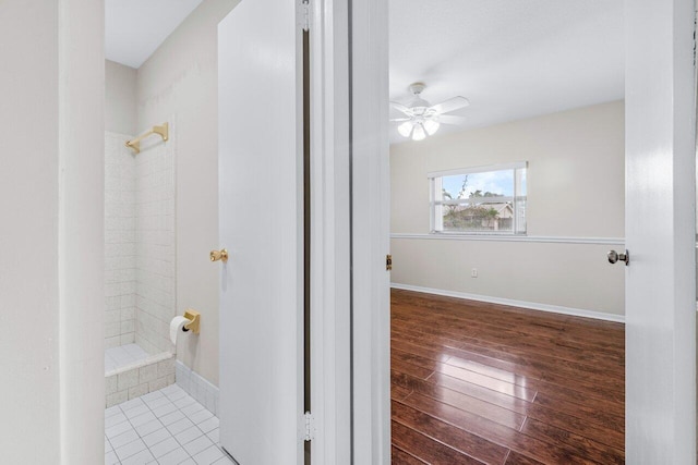 bathroom featuring ceiling fan, wood-type flooring, and tiled shower