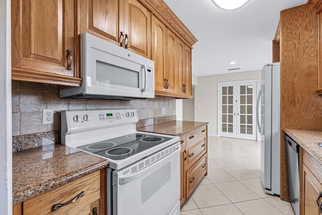 kitchen featuring light tile patterned floors, dark stone countertops, backsplash, stainless steel appliances, and french doors