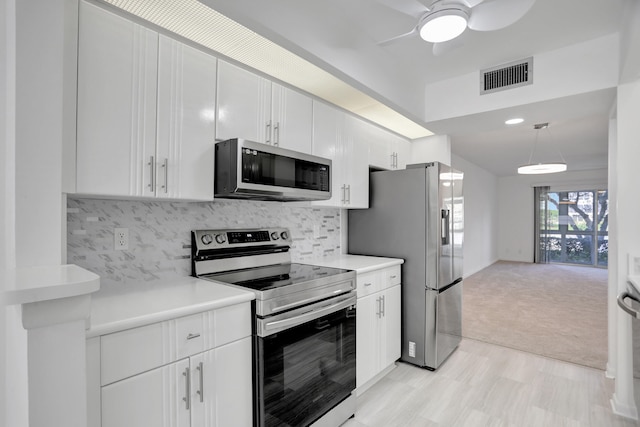 kitchen featuring stainless steel appliances, light colored carpet, ceiling fan, white cabinetry, and tasteful backsplash