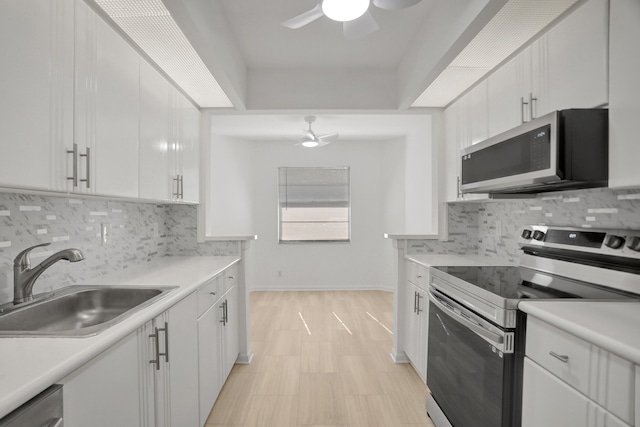 kitchen featuring ceiling fan, stainless steel appliances, backsplash, and white cabinetry