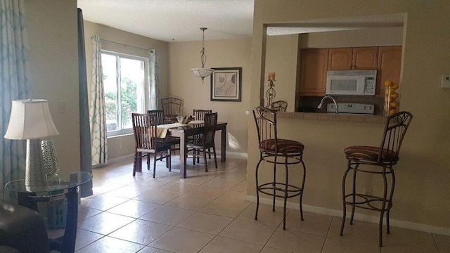 tiled dining room with a textured ceiling and sink