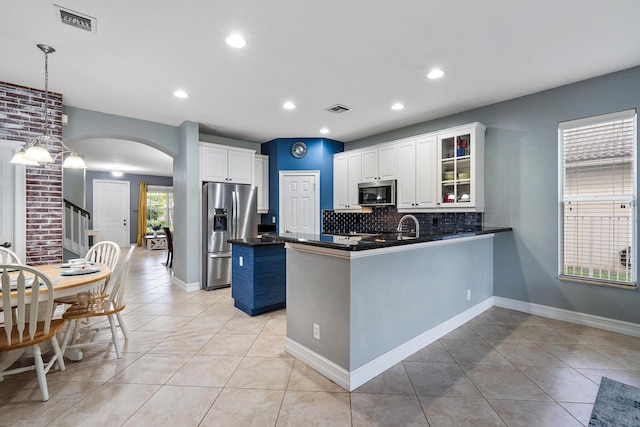 kitchen featuring appliances with stainless steel finishes, light tile patterned flooring, backsplash, hanging light fixtures, and white cabinets