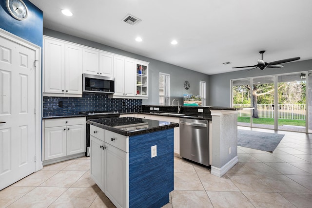 kitchen featuring stainless steel appliances, light tile patterned flooring, a center island, white cabinets, and ceiling fan