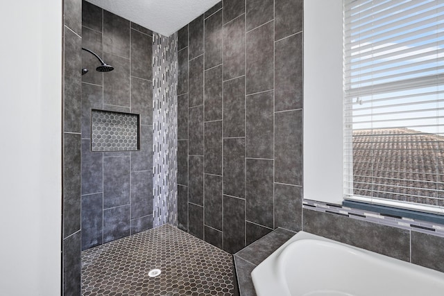 bathroom with shower with separate bathtub and a textured ceiling